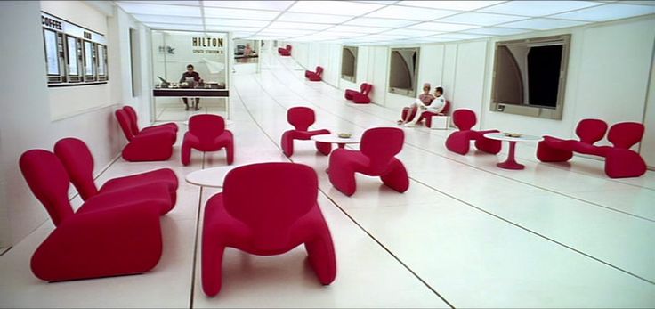 Futuristic furniture: sleek white floors and ceilings, contrasting with scarlet Koonsian chairs in 2001: A Space Odyssey.