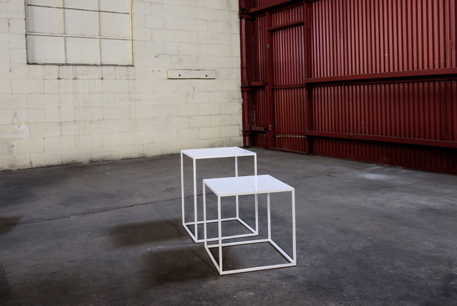 Two powder-coated white end tables, examples of futuristic furniture, by Patrick Cain Designs.
